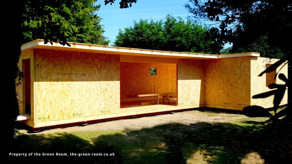 Garden room under construction with timber frame structure in outdoor setting