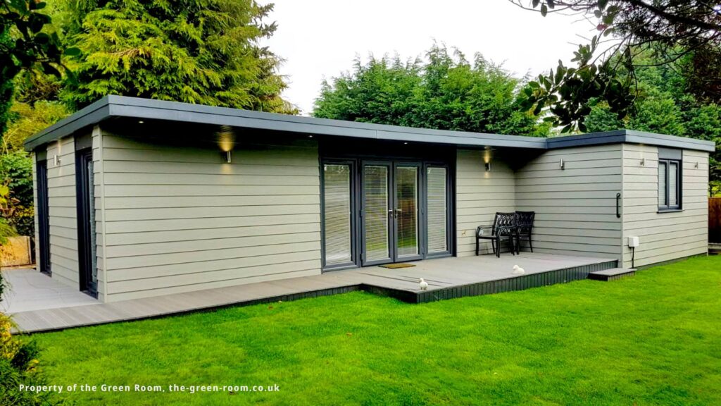 Modern insulated garden room with flat roof and patio doors in landscaped garden