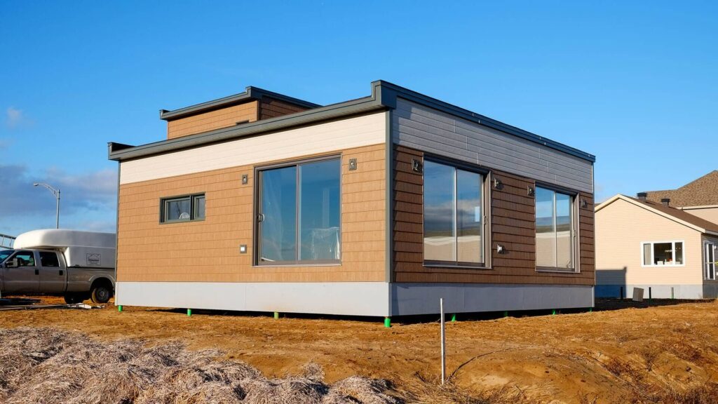 Modern modular home exterior with timber cladding and large windows on raised foundations